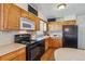 Kitchen featuring wood cabinets, black appliances, and efficient layout at 6882 Moore St, Arvada, CO 80004