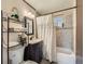 Bathroom with a shower-tub combo, patterned tile, and dark vanity at 7310 Carnation Pl, Commerce City, CO 80022