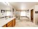 Bright bathroom featuring a soaking tub, walk-in shower, and double sink vanity with framed mirrors at 24191 E Iowa Pl, Aurora, CO 80018