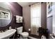 Cozy half bathroom featuring a pedestal sink, dark colored walls, and natural light from window at 24191 E Iowa Pl, Aurora, CO 80018