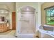 Bathroom with glass shower door, wood vanity, and bright windows at 7800 Indiana St, Arvada, CO 80007