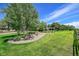 Expansive front yard featuring lush green grass, mature trees, and a charming pergola at 7800 Indiana St, Arvada, CO 80007