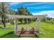 Covered pergola with seating overlooks the expansive lawn and mature trees at 7800 Indiana St, Arvada, CO 80007