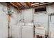 Basement with a white washer and dryer, utility sink, and exposed ceiling at 6991 Warren Dr, Denver, CO 80221