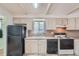 Bright kitchen with white cabinets, black appliances, and a double basin sink under the window at 6991 Warren Dr, Denver, CO 80221