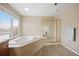 Bathroom features tile-surround tub under a window, shower with gold trim, and wood-look flooring at 13078 Monaco Way, Thornton, CO 80602