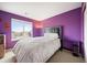 Bedroom featuring purple walls, large windows with natural light, and a comfortable bed at 13078 Monaco Way, Thornton, CO 80602