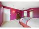 Bedroom with purple walls, neutral carpet, a wooden dresser, and an arched entry to the Primary bath at 13078 Monaco Way, Thornton, CO 80602