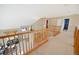 View of the home's loft with wood banisters overlooking the entry and living room, plus neutral paint and carpet at 13078 Monaco Way, Thornton, CO 80602