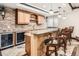 Finished basement bar with stone wall, wooden cabinets, and granite countertop with barstools at 4586 Carefree Trl, Parker, CO 80134