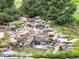 Close-up of a backyard waterfall feature surrounded by lush greenery and stone at 4586 Carefree Trl, Parker, CO 80134
