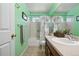 Green bathroom featuring a shower over tub combo, single sink vanity and neutral tile at 16278 E 105Th Way, Commerce City, CO 80022