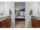 A view between two bathroom vanities into a bedroom with a large bed and window with blinds at 16278 E 105Th Way, Commerce City, CO 80022