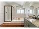 Bathroom with a soaking tub, glass enclosed shower, green painted cabinets and stone counter tops at 1774 Brookside Dr, Highlands Ranch, CO 80126