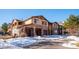 Tan and stone three-story townhouse with three-car garage and snowy landscape at 9876 W Freiburg Dr # G, Littleton, CO 80127