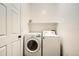 A bright laundry room with washer, dryer, and storage shelf at 7626 Depew St # 102, Arvada, CO 80003