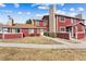 Charming townhouse with red siding, stone chimney, well-maintained lawn, and inviting curb appeal at 8424 Everett Way # E, Arvada, CO 80005