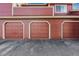 A close up view of a multi-unit exterior featuring a three-car garage with a red brick facade at 8424 Everett Way # E, Arvada, CO 80005