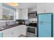 Bright kitchen features stainless steel appliances, white cabinetry, butcher block countertops, and vintage turquoise refrigerator at 1740 Trenton St, Denver, CO 80220