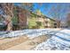 Exterior view of a green condominium building with brick accents and balconies in a winter setting at 2800 Kalmia Ave # B209, Boulder, CO 80301