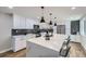 Modern kitchen with white cabinets, quartz countertops, and a large island at 7076 S Newland St, Littleton, CO 80128