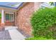 A close up of the brick exterior leading to the front door and window, lush green shrubs, and dark rocks at 2247 S Lima Ct, Aurora, CO 80014