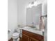 Bright half bath with cherry wood cabinets, granite countertop, and a decorative mirror at 7814 S Grand Baker Ct, Aurora, CO 80016