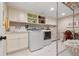 Bright laundry room with upper and lower cabinets, laundry sink, washer, dryer, and built-in shelving at 10 Oakmont Ln, Littleton, CO 80127