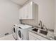 Bright laundry room with modern washer, dryer, and granite countertop sink at 5134 Cupule Trl, Castle Rock, CO 80104