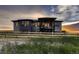 Backyard of large modern house with fence and grassy field at sunset at 8868 Geyser Peak Way, Parker, CO 80138