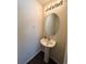 A half bath features a pedestal sink, an oval mirror, and a modern light fixture at 47373 Lily Ave, Bennett, CO 80102