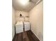 Well-lit laundry room with modern washer and dryer, plus overhead shelving for storage at 47373 Lily Ave, Bennett, CO 80102