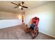 A carpeted living room boasts a ceiling fan and a whimsical ski chair by a white half-wall at 47373 Lily Ave, Bennett, CO 80102