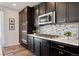Close-up of a modern kitchen with stainless steel appliances, dark cabinets, and a stylish backsplash at 16268 Mount Silverheels Way, Broomfield, CO 80023