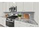 Granite countertops, stainless steel appliances, and gray backsplash highlight the modern kitchen at 24447 E Ada Ave, Aurora, CO 80018