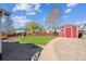 Spacious backyard with lawn, wood deck, gravel pathway and a red shed, surrounded by a privacy fence at 765 Freestone St, Brighton, CO 80603