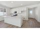 Bright kitchen featuring white cabinets, a large island, stainless steel appliances, and wood-style flooring at 1306 Sienna Peak Cir, Erie, CO 80516