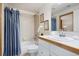 Well-lit bathroom showcasing a shower with blue curtain and a vanity with white cabinets and a wood-trimmed countertop at 4405 Fairway Ln, Broomfield, CO 80023