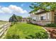 Lush backyard featuring green grass, white fence, stone accents, views of mature trees, and well maintained landscaping at 4405 Fairway Ln, Broomfield, CO 80023