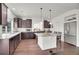 Open kitchen with an island, stainless steel refrigerator, and dark cabinets at 4996 Cathay Ct, Denver, CO 80249