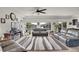 Bright living room featuring a large gray area rug, a ceiling fan, and windows providing plenty of natural light at 4996 Cathay Ct, Denver, CO 80249