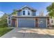 Charming two-story home featuring a three-car garage, blue siding, brick accents, and manicured lawn at 5645 S Himalaya Way, Centennial, CO 80015