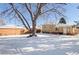 Large backyard with shed, mature trees, and home view in winter at 2595 S Utica St, Denver, CO 80219