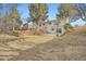 Large backyard showcasing a retaining wall, mature trees, patio, and the rear of the house at 6233 W 75Th Ave, Arvada, CO 80003