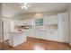 Bright kitchen with white cabinets, laminate flooring, and a functional island at 6522 S Hoyt Way, Littleton, CO 80123