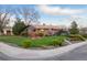 Well-maintained brick home featuring lush green lawn, mature trees, and manicured shrubbery at 8079 W 67Th Ave, Arvada, CO 80004