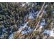 Aerial view of a cabin and surrounding snowy forest landscape at 5925 Herzman Dr, Evergreen, CO 80439