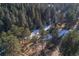 Aerial view showcasing a cabin in a snow-dusted forest setting at 5925 Herzman Dr, Evergreen, CO 80439