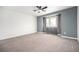 A spacious carpeted bedroom featuring a ceiling fan, gray accent wall, and bright window at 6920 W 48Th Ave, Wheat Ridge, CO 80033