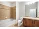 Bathroom featuring tiled shower-tub, toilet, and wood vanity with sink and decorative mirror at 7865 Vallagio Ln # 308, Englewood, CO 80112